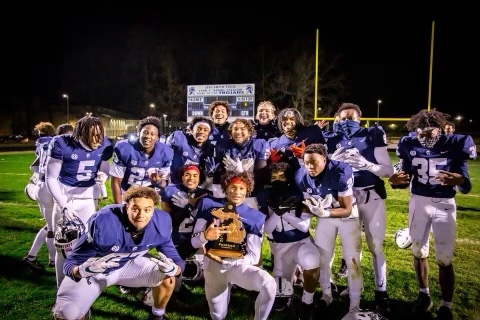 football team posing at nighttime on the football field celebrating their win