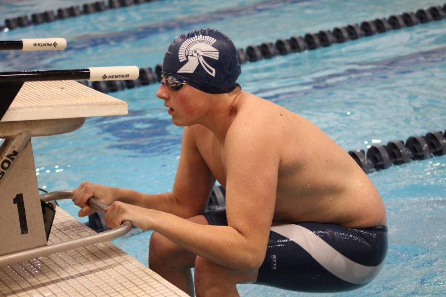 Boy+pulling+himself+into+or+out+of+the+pool+with+a+blue+swim+cap