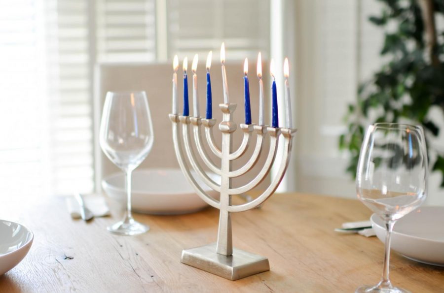 Blue and white menorah with all candles lit in the center of a table