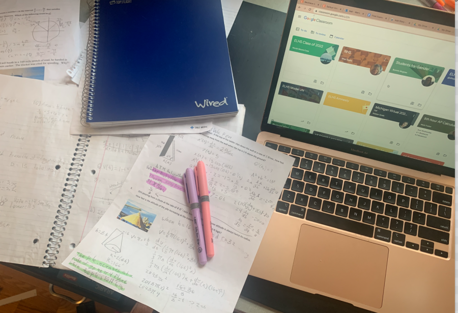 Notes and books on a desk next to a laptop with 2 highlighters