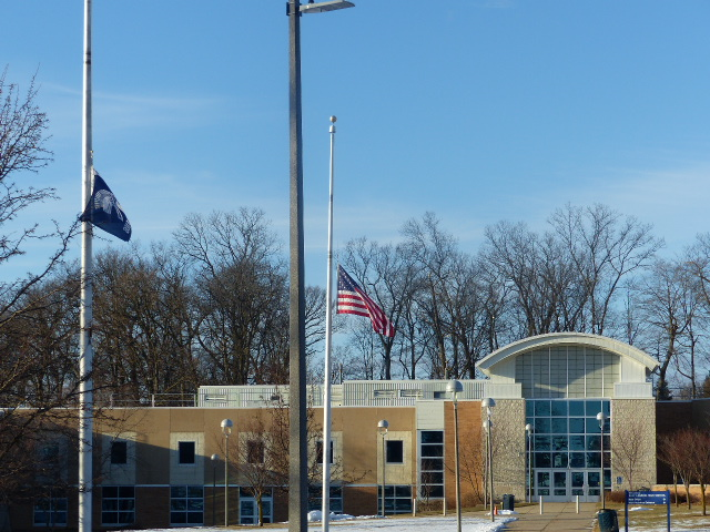 East Lansing High School. Two flags are in front-The American flag, and the high school flag.