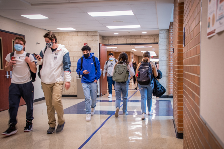 Students walking in the hallway with masks on. 