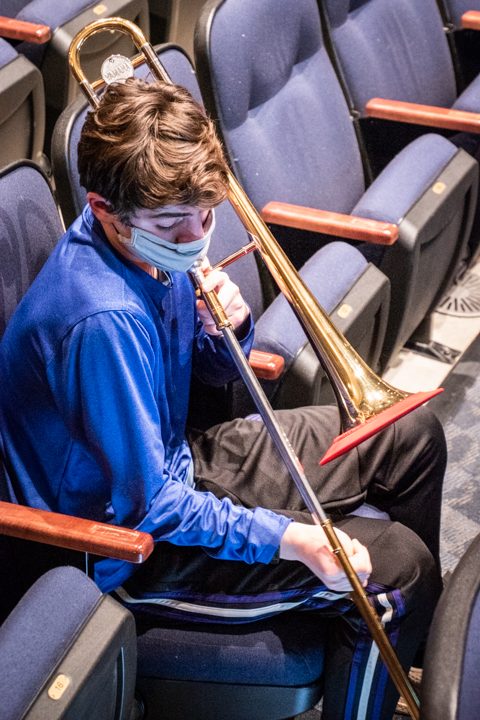 Raphael Gold (10) plays his trombone while wearing a special musician mask. "Bell cover" is attached on his trombone. 