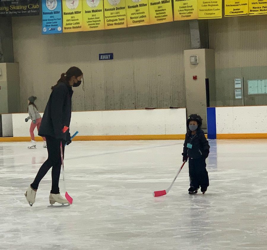 Eliza Morman (11) skates around with a young boy, who she is teaching hockey to, while volunteering at Learn to Skate on Dec. 5.