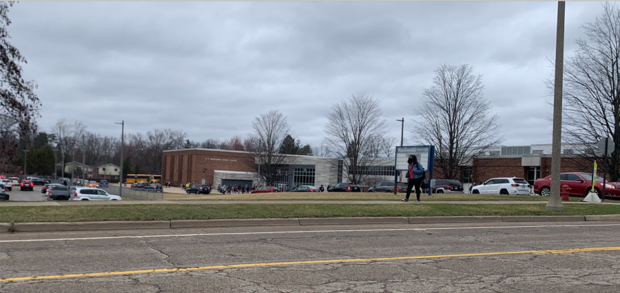 Student walks next to brown building on grey day