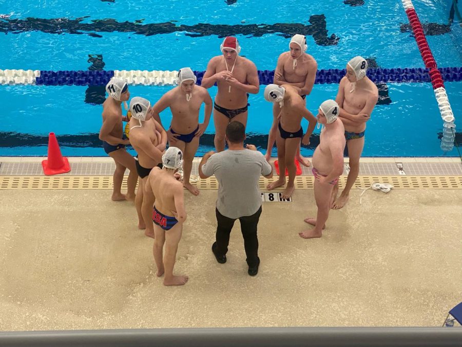 Pausing for a timeout, the waterpolo team talks strategy with their coach. 