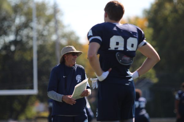 head coach Bill Feraco speaks to Charlie Baker (12) at practice