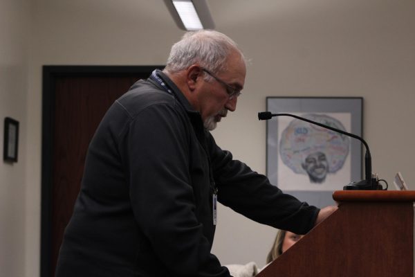Hunching over the podium, Mark Pontoni reads his statement in defense of Petrowitz to the school board meeting on Oct. 9 