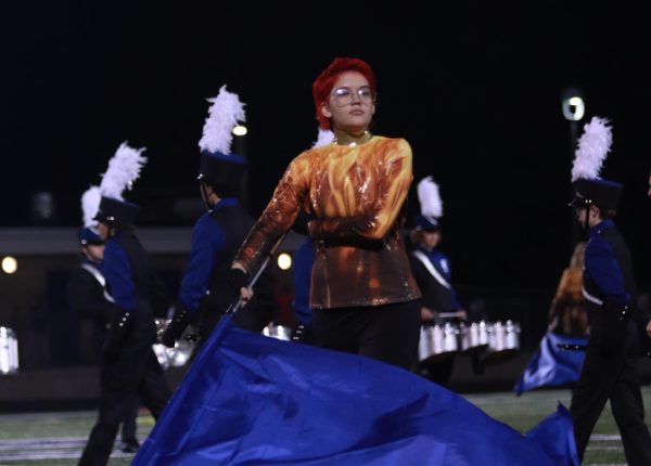 Readying their flag, Reid Hoogstraten (9) performs during the homecoming football game alongside the marching band and the color guard team. Hoogstratens participation went further than color guard from also being a member of the winter guard team.