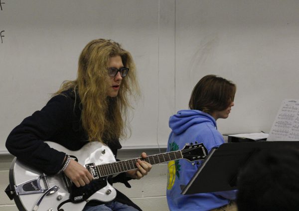 While at rehearsal for Jazz II, Liam VanDerHeide (10), strums his part on the guitar along to the music on Dec. 12. VanDerHeide will be performing at Collage for the second year in a row on Jazz II. 