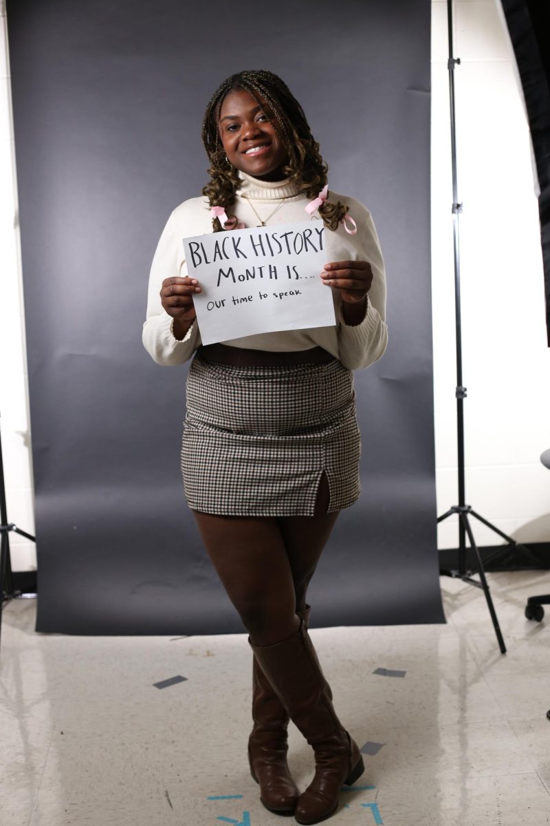 Gabrielle Sewavi (12) stands holding a sign that reads Black History month is our time to speak.