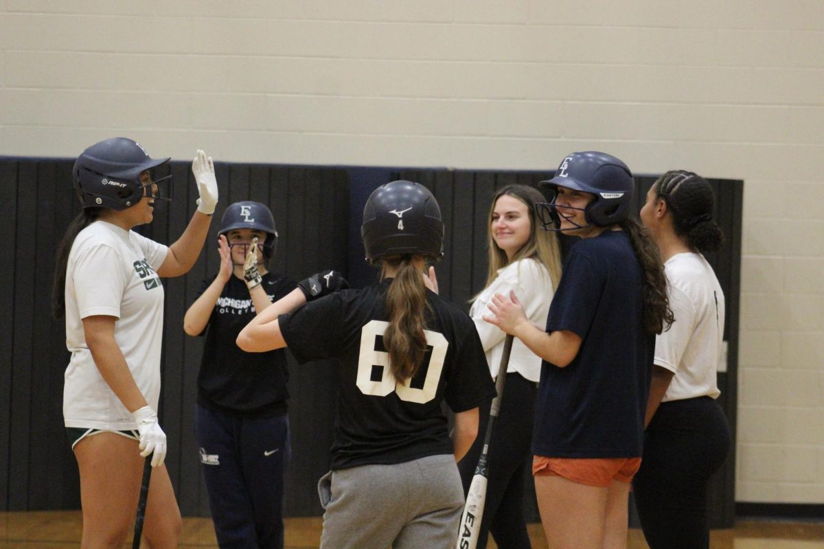 Softball team gathers around after batting practice in the auxiliary gym on Dec. 8. The players have been meeting on Sunday afternoons to prepare for their main spring season.