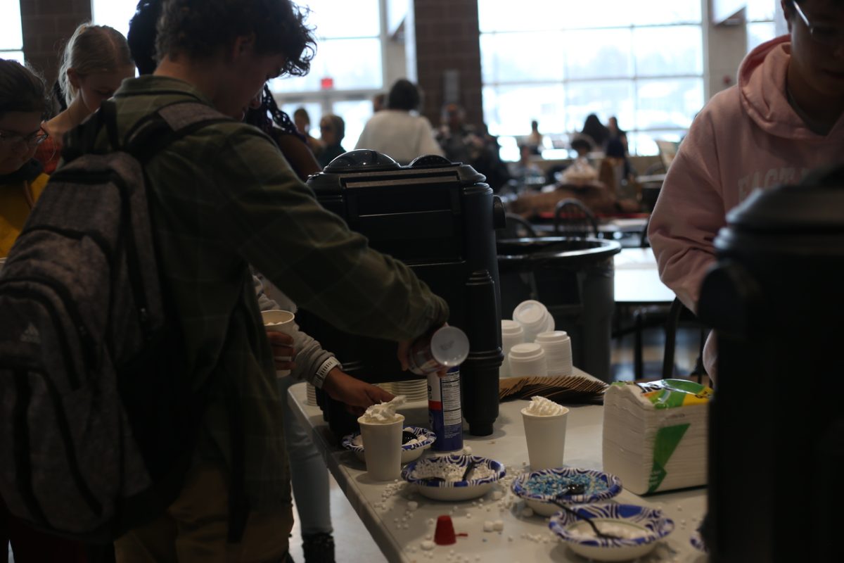 Standing in the line for cocoa, Sullivan Phillip (10) adds whipped cream to his cup.