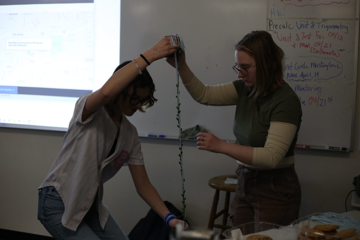 Kelly Maier (12) and Samantha Tuinstra (12) decorate their graduation cords with leaves during the Students for Environmental Action meeting.