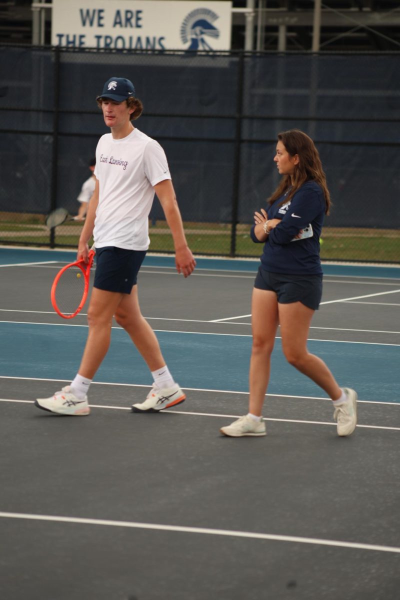 Walking while talking, coach Alexandra Cross gives strategies and advice to Miles Johnston (12). Cross is the wife of the official varsity boys' coach, Cody Cross, as well as a devoted tennis player. 