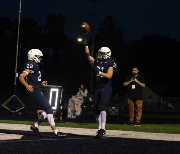 Cameron White (10) and Baylor Schanski (11) celebrate after Schanski scored a touchdown during the homecoming game against Okemos Friday, Sep. 21.