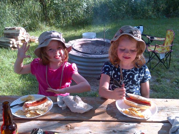 As a young child, Maureen Rojewski (12) eats a hotdog on a family camping trip alongside her sister, Gretchen Rojewski. 