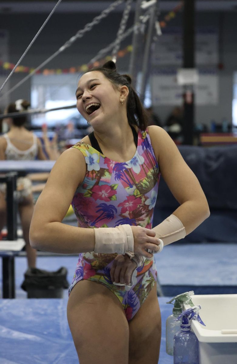 Laughing, Kaiya Johnson (10) chalks her hands during practice at Capital City Flips on Friday, Dec. 5. Johnson competed through Capital City Flips for the past four years after she and her family moved to East Lansing from South Carolina. Photo by Aya Howard.