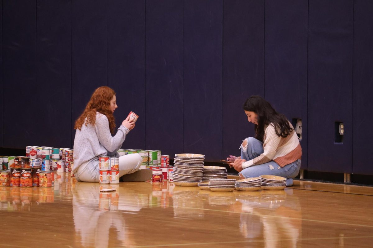 Preparing for the Turkey Drive, Cielo Gutierrez (12) and Liliane Klotz (12), members of NHS, carefully sort pumpkin cans and pie crusts for the food bags on Nov. 21. Over 30 boxes of donations were collected and distributed to families before Thanksgiving break. 