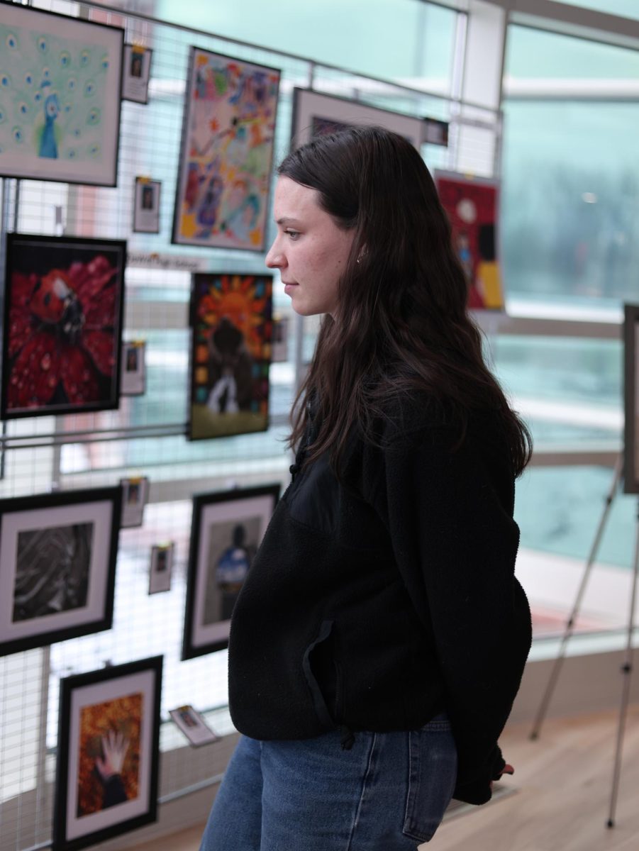 Gazing at the art, Mariana Kribs (11) visits the MSUFCU main building on Feb. 4. Local high schools provided art for viewing, and Kribs created a oil pastel piece of her dog, Loki, for the show. 