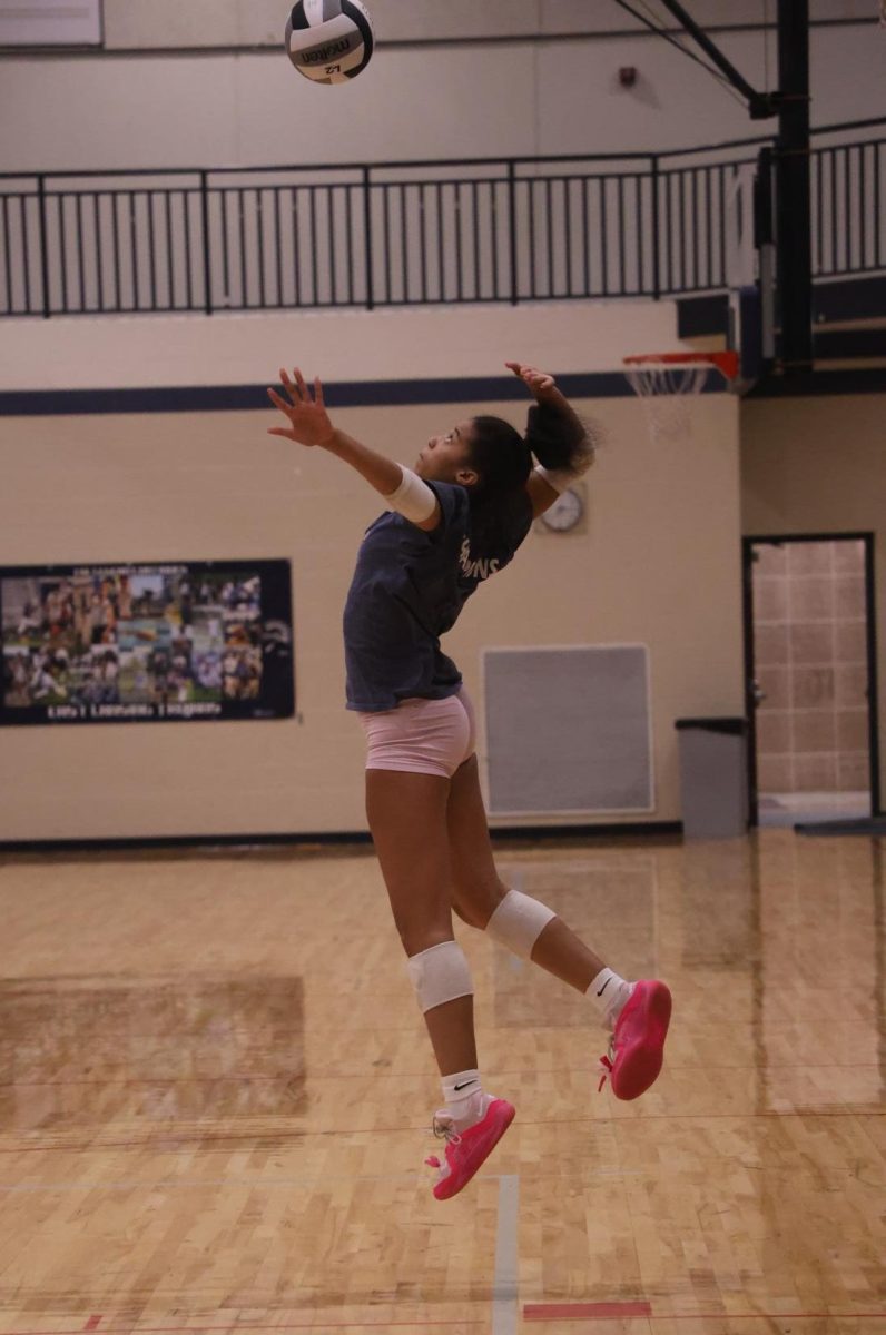 Reaching for the ball, Ariyanna Johnson (12) leaps into the air. Players had to jump, dive and defend as quickly as possible in order to keep the ball in the air, the main goal of volleyball. 
