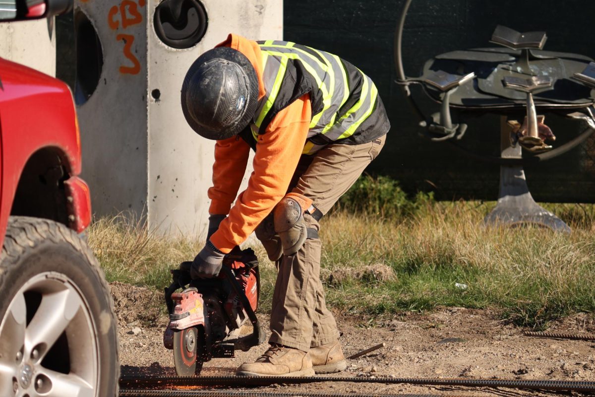 Slicing clean into metal sections, a
construction worker prepares building
parts on Oct. 29. Many different jobs went
on at the same time in order to build the
site up efficiently, like hammering pieces
together or moving supplies from place to
place.