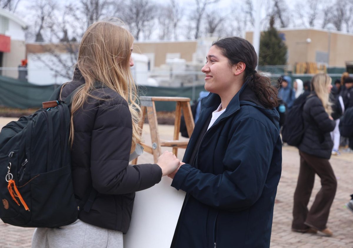 Holding hands with Clara Keith (11), Jessica Mielock (12) smiles wistfully. Mielock was one of several students who spoke at the walkout.

