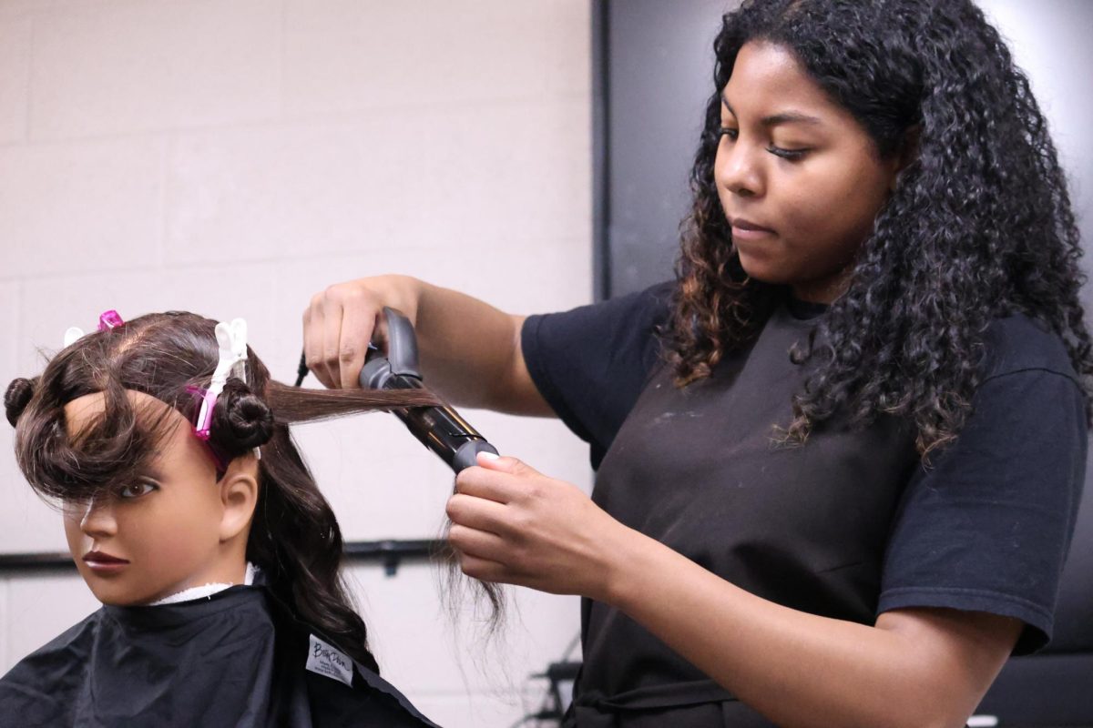 Chloe Scates (12) styles the hair of a mannequin at Wilson Talent Center during class on March 6. She has loved doing hair since she was a little girl.