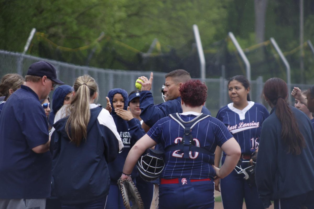 Addressing his team, new varsity softball Corey Cataline wraps up the April 27 game. Cataline joined the team this year, inspired by past coaching and family softball experience.