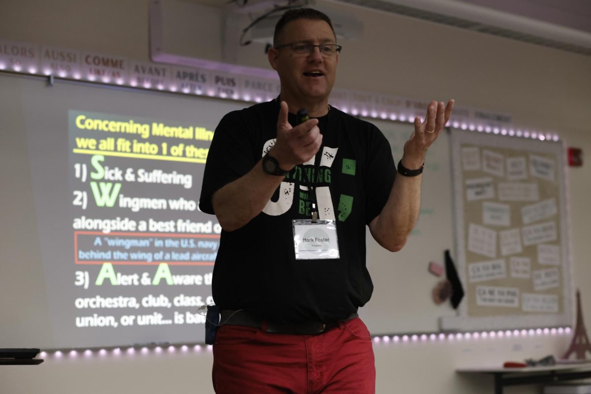 Standing in front of the whiteboard, Mark Foster presents "Singers. whistlers, and AYOers"  during the Mental Health Summit at ELHS on April 29.  He shared his story of his battle with depression with students the day before during excel before sharing with community members.